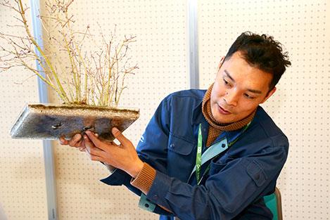 根が見える特殊な鉢で説明する小棚さん