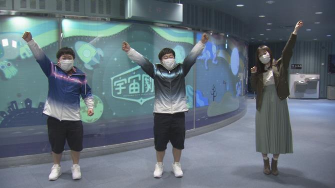 宇宙劇場の前でポーズをとる出演者の写真