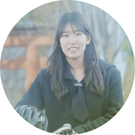 自然光の中、長い髪の女性がカメラを見つめ、落ち着いた雰囲気を感じさせる人物写真